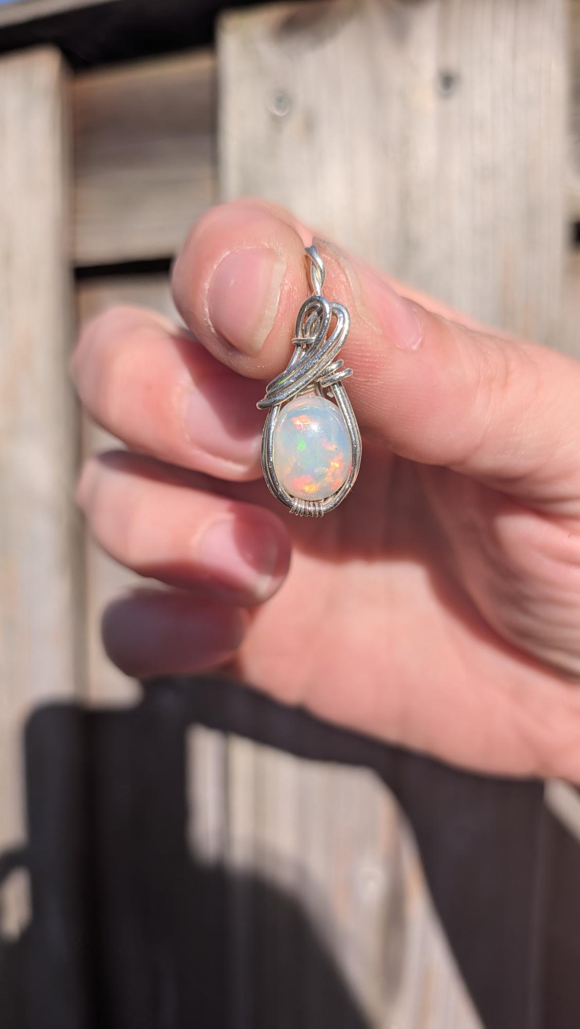 Massieve handgemaakte hanger met witte Welo opaal en dik sterling zilveren vlechtwerk in het zonlicht, zoals getoond op shared image (30).jpg.