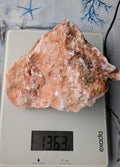 Een fors, onbewerkt blok Zonnesteen van 1363 gram met warme oranje-rode tinten en natuurlijke glinstering, gepresenteerd op een neutrale ondergrond.