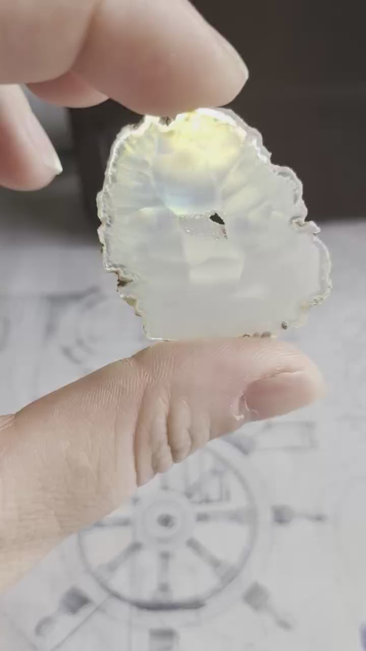 Video van een 4 cm Iris Agaat; bij het bewegen voor het licht ontstaat een heldere en felle irisatie over de transparante kristalstructuur.