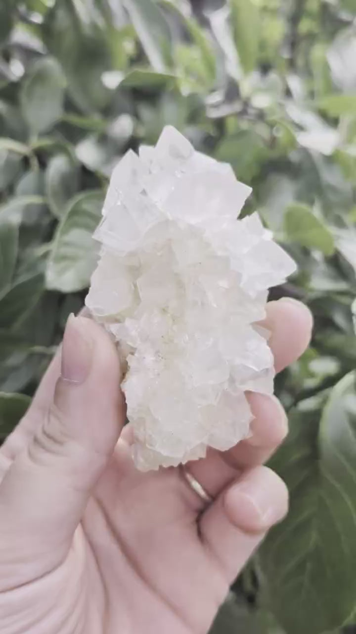 Een hand houdt een gedetailleerd en helder calciet cluster uit Indonesië van 94 gram vast, met een unieke, natuurlijke kristalstructuur