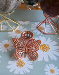 Sierlijke roségoudkleurige metalen bollenhouder met een vlinder. 2 cm ring, geschikt voor edelsteen bollen van 3 tot 6 cm. Prijs 6,95 euro.
