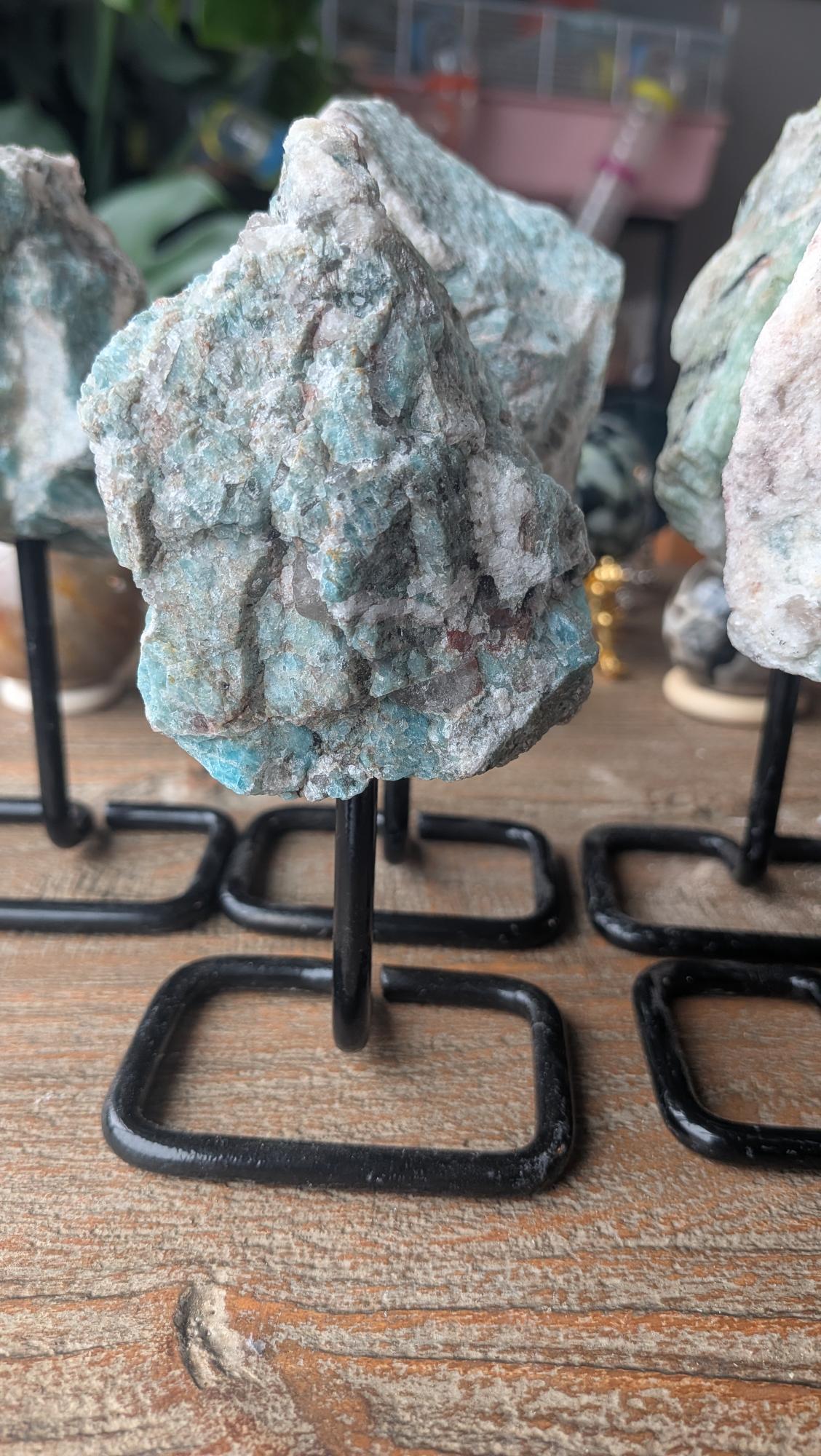 Laatste unieke exemplaar van een ruwe Amazoniet edelsteen op zwarte standaard, item #212, wegend 270 gram en 14 cm hoog.