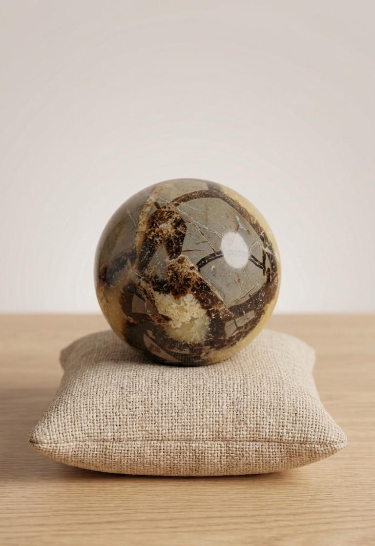 Gepolijste Septarie bol van 5 cm met opvallende gele calciet aders en donkere breuklijnen op een linnen kussentje, prijs 17,50 euro. Oeroude aarding edelsteen.