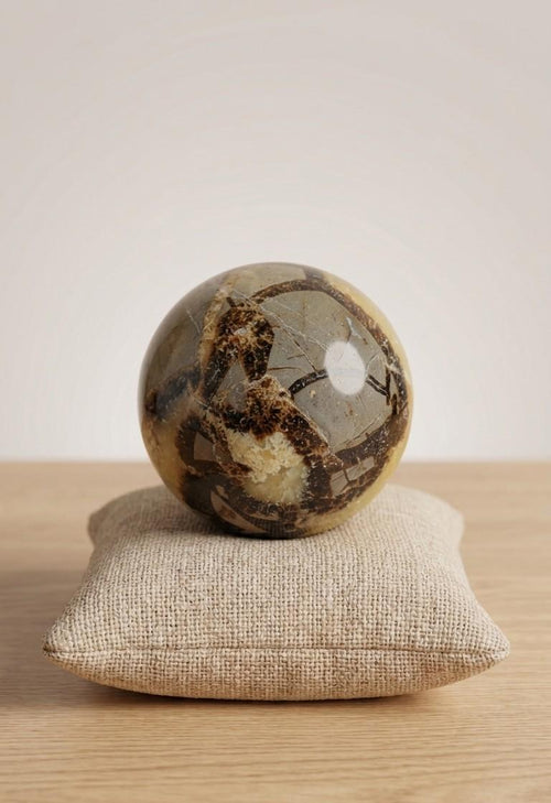 Gepolijste Septarie bol van 5 cm met opvallende gele calciet aders en donkere breuklijnen op een linnen kussentje, prijs 17,50 euro. Oeroude aarding edelsteen.