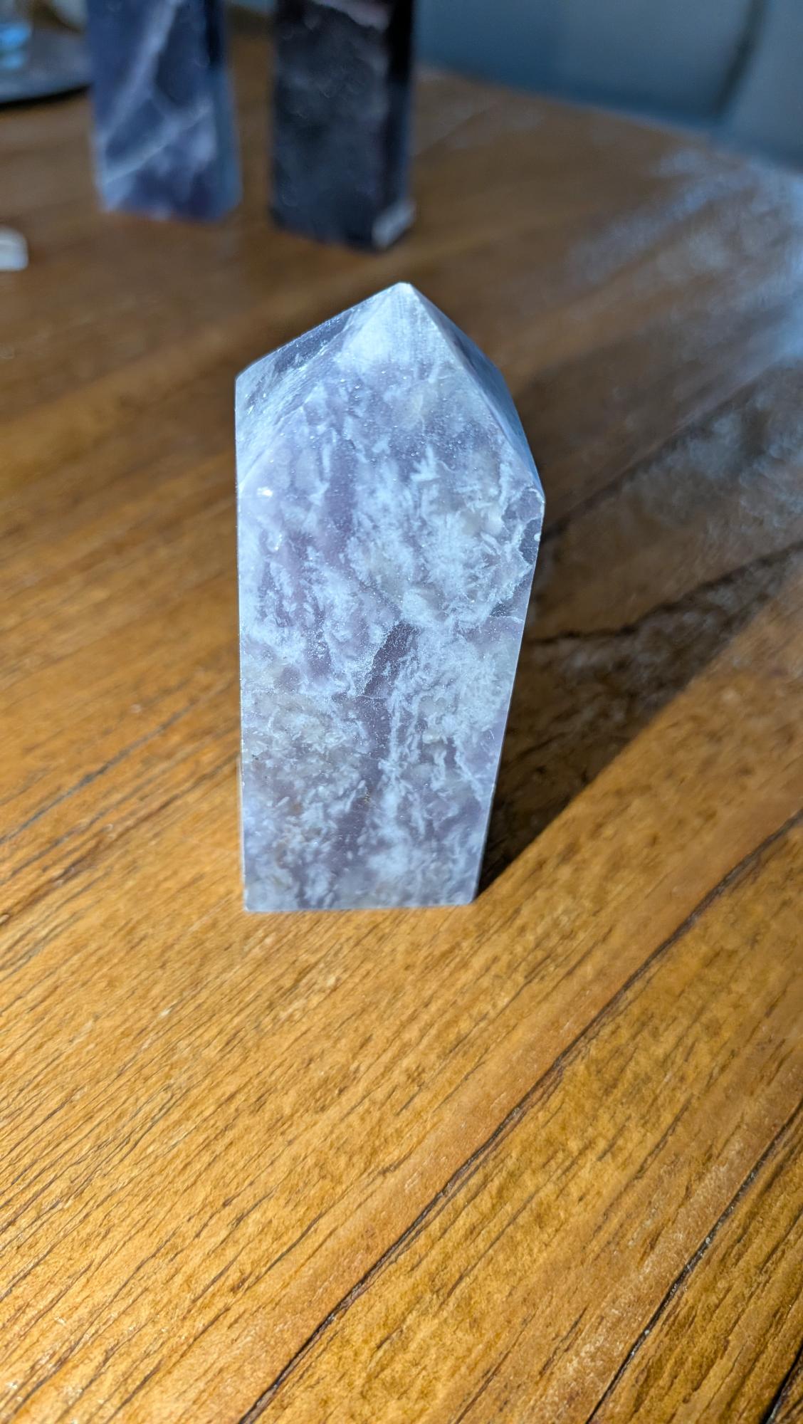 Robuuste paarse Lepidoliet kristal toren van 7 cm hoog met zilveren glinsteringen op een houten ondergrond.