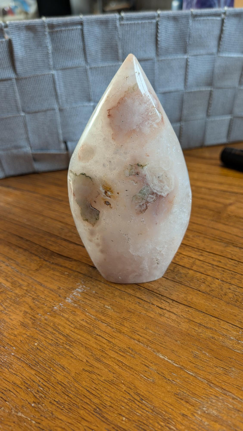 Gepolijste punt van Bloemagaat met zachte roze en witte patronen op een houten ondergrond, 10 cm hoog en 245 gram.