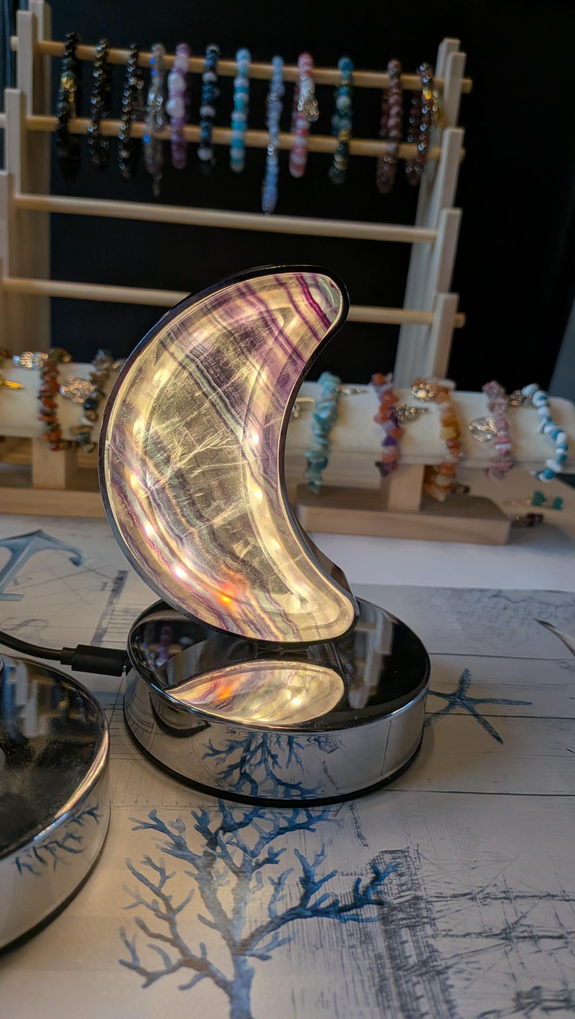 Luxe edelsteen lamp van Regenboog Fluoriet in de vorm van een halve maan met paarse en groene banden, brandend op een chromen voet.