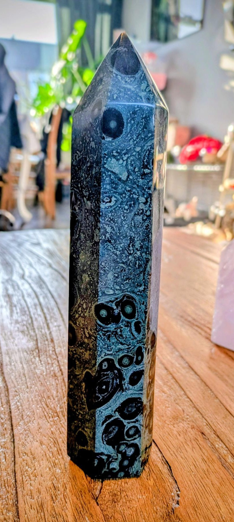 "Zeer grote, gepolijste Kambaba Jaspis tower met donkergroene cirkelpatronen op een houten ondergrond."