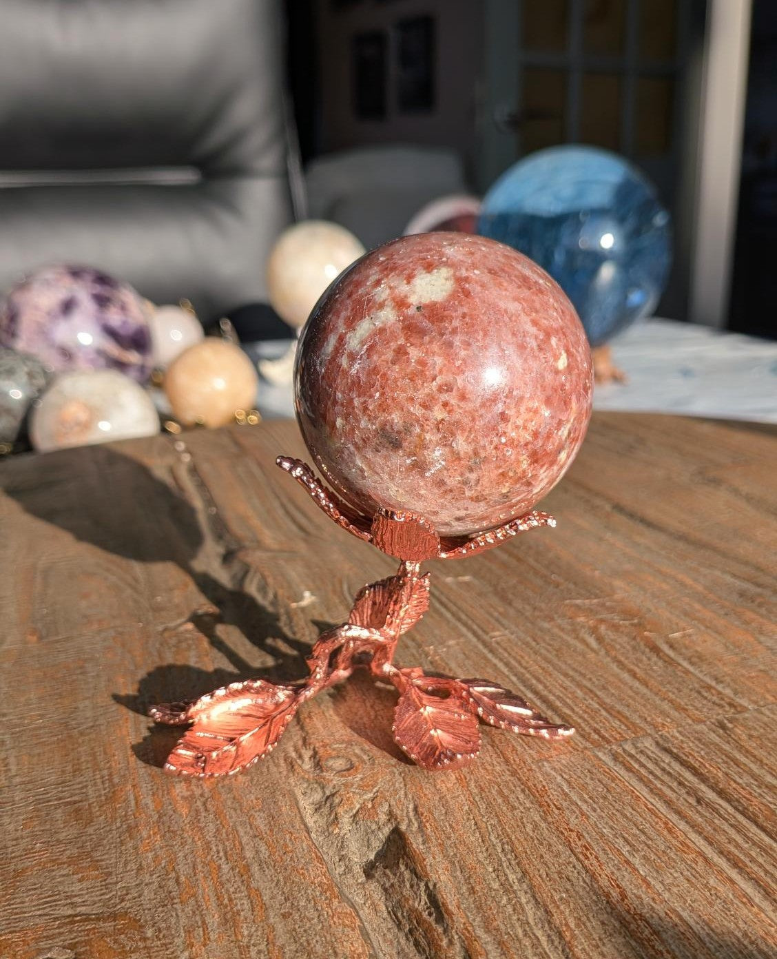 Glinsterende gouden Zonnesteen bol van 6 cm diameter op een luxe roségoudkleurige standaard in de vorm van een bloem met bladeren