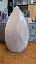"Indrukwekkende XL Rozenkwarts vrije vorm van 20 cm hoog en 1936 gram, met zachte roze tinten en een gepolijste glans op een houten ondergrond."