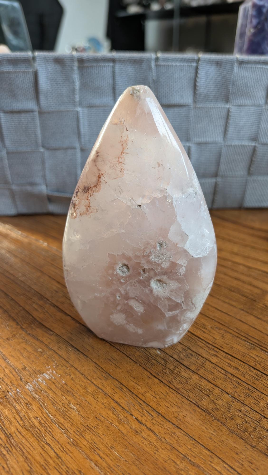 Slanke Bloemagaat punt met witte bloempatronen en roze tinten, 10,5 cm hoog en 190 gram, op een houten ondergrond.