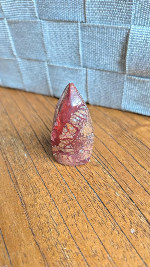 "Kleine gepolijste Crazy Lace Agaat vrije vorm met dieprode en bruine patronen, 4 cm hoog en 21 gram, staand op een houten ondergrond."