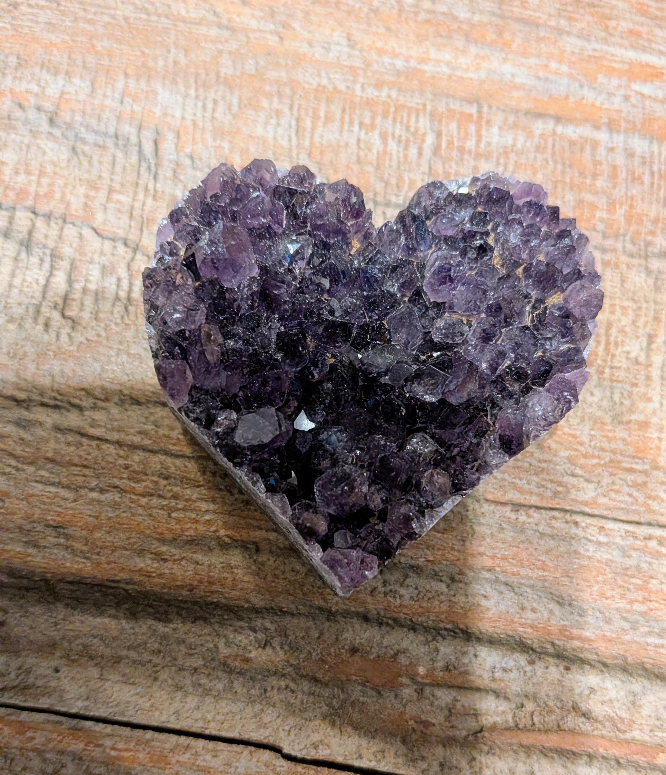 "Zijaanzicht van een Amethist hart waarin de overgang tussen de ruwe geode-rand en de gepolijste achterkant zichtbaar is."