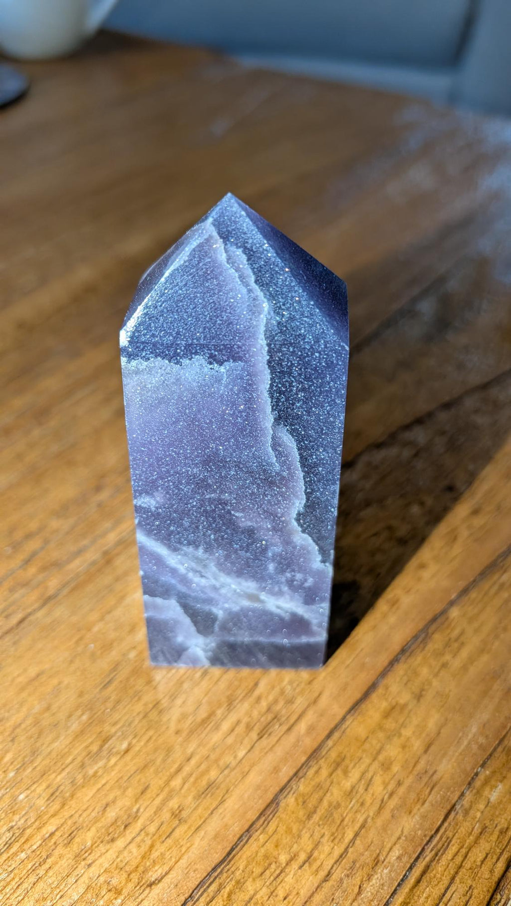 Verticale paarse Lepidoliet kristal toren van 8 cm hoog op een houten achtergrond, gewicht 99 gram.