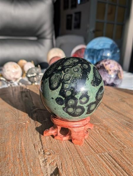 Donkergroene Kambaba Jaspis bol van 7 cm diameter en 583 gram met zwarte patronen op een luxe bewerkte houten standaard