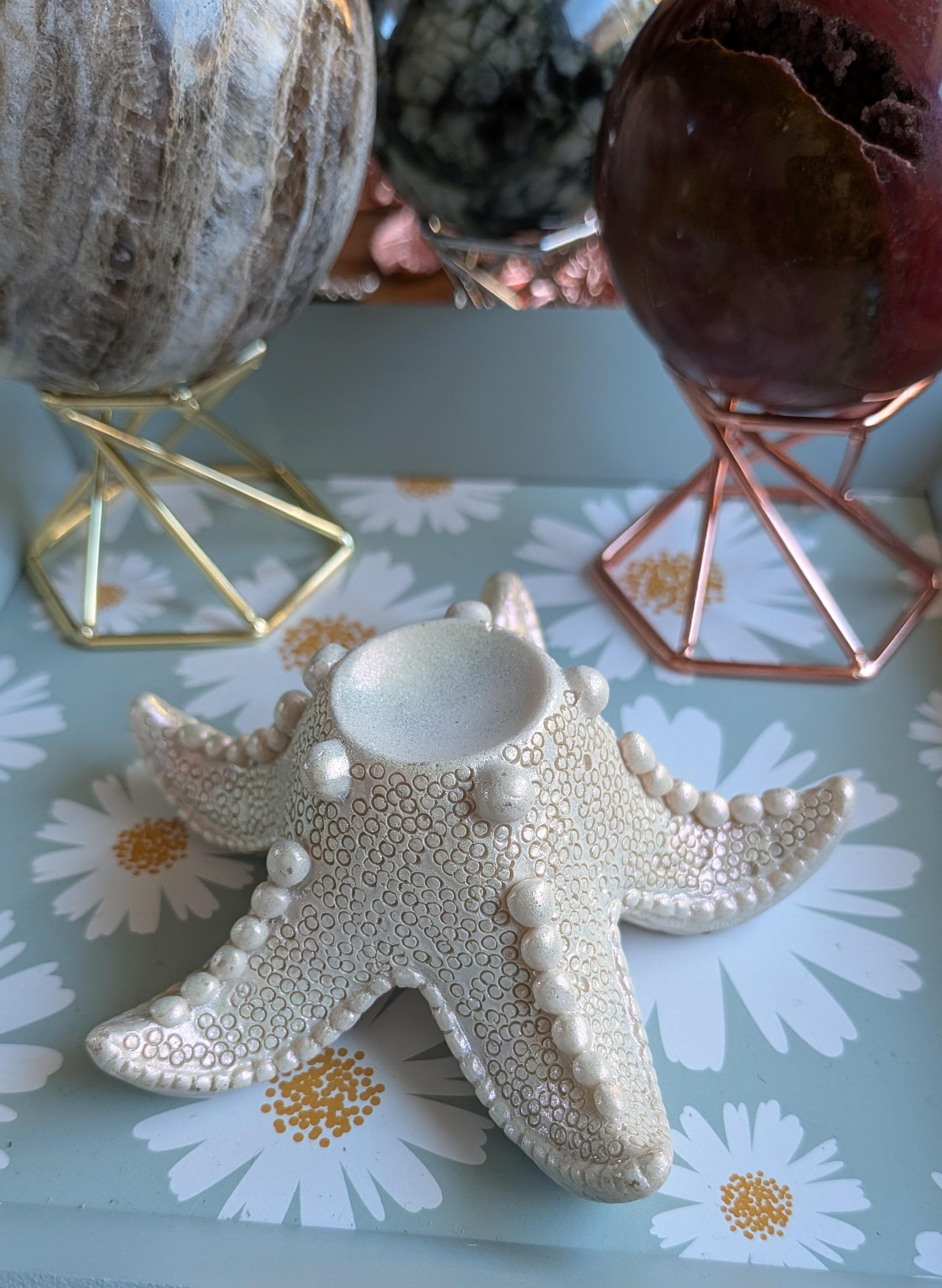Luxe witte zeester bollenhouder met parelmoerglans, 10 cm breed met een 3,5 cm binnenring. Decoratief oceanisch display voor edelsteen bollen, prijs 12,50 euro.